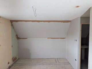 Plasterboard fitted to a sloping wall and doorway in a loft room.