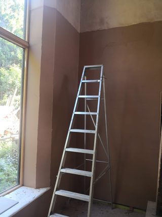 Fresh plaster to a tall wall and window reveal beside an aluminium stepladder.