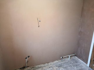 Freshly plastered wall and internal corner with pipe and cable outlets.
