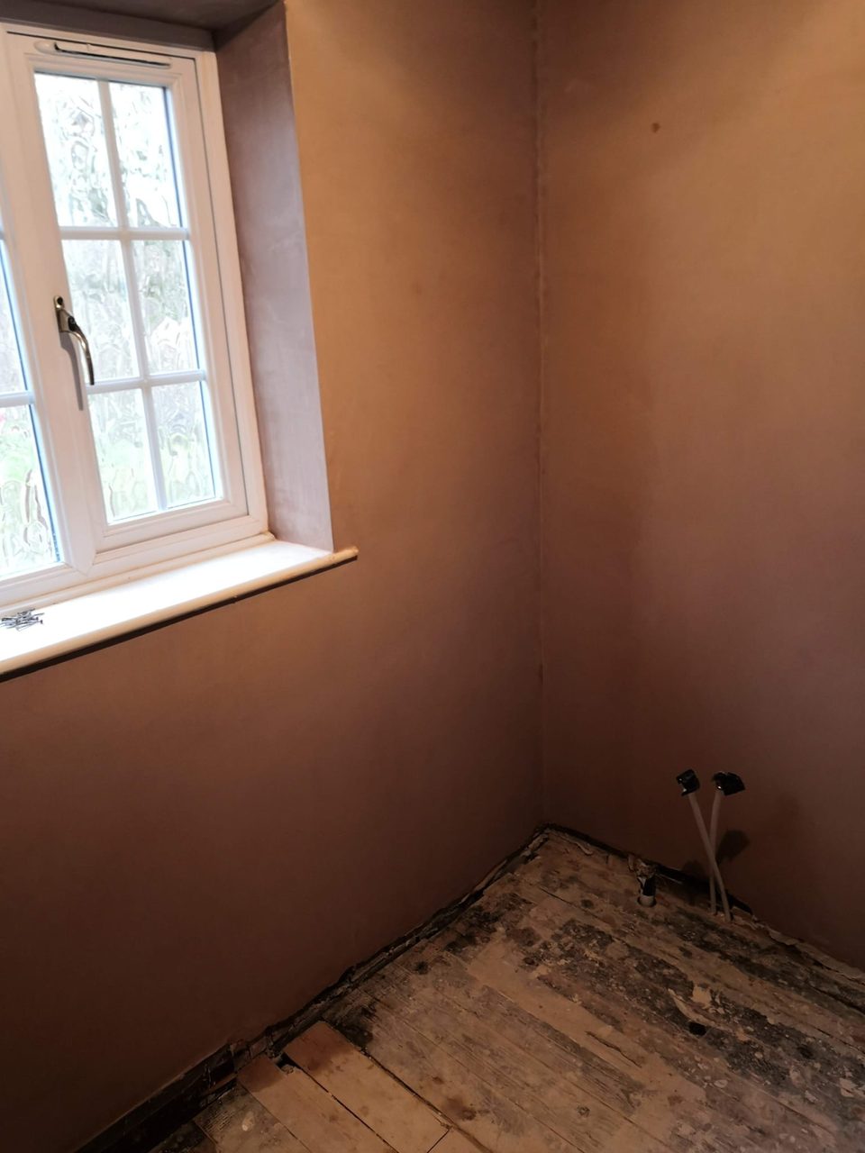 Freshly plastered corner and window reveal beside a frosted window.